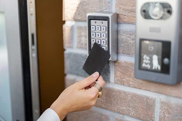 A woman's hand holding a key card accessing a security system by a door